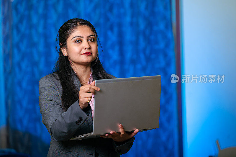 快乐的年轻亚洲/印度女孩拿着笔记本电脑的肖像